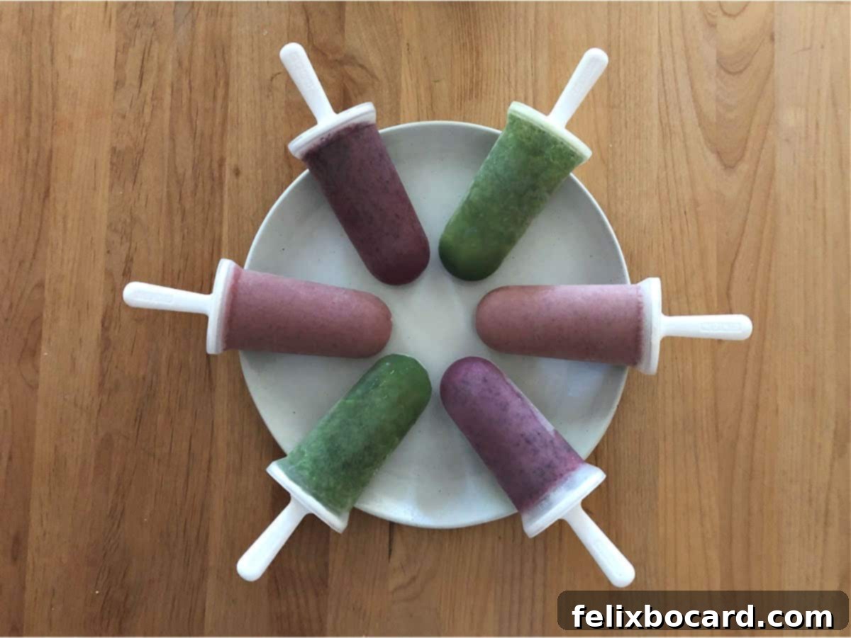 Six vibrant smoothie popsicles arranged in a circular pattern on a crisp white plate, showcasing their refreshing appeal.