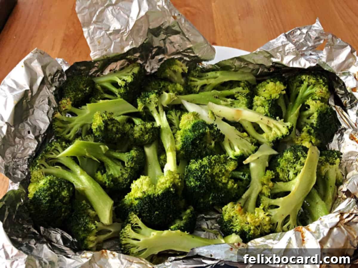 Close-up of an opened foil packet revealing perfectly grilled broccoli florets with a slight char