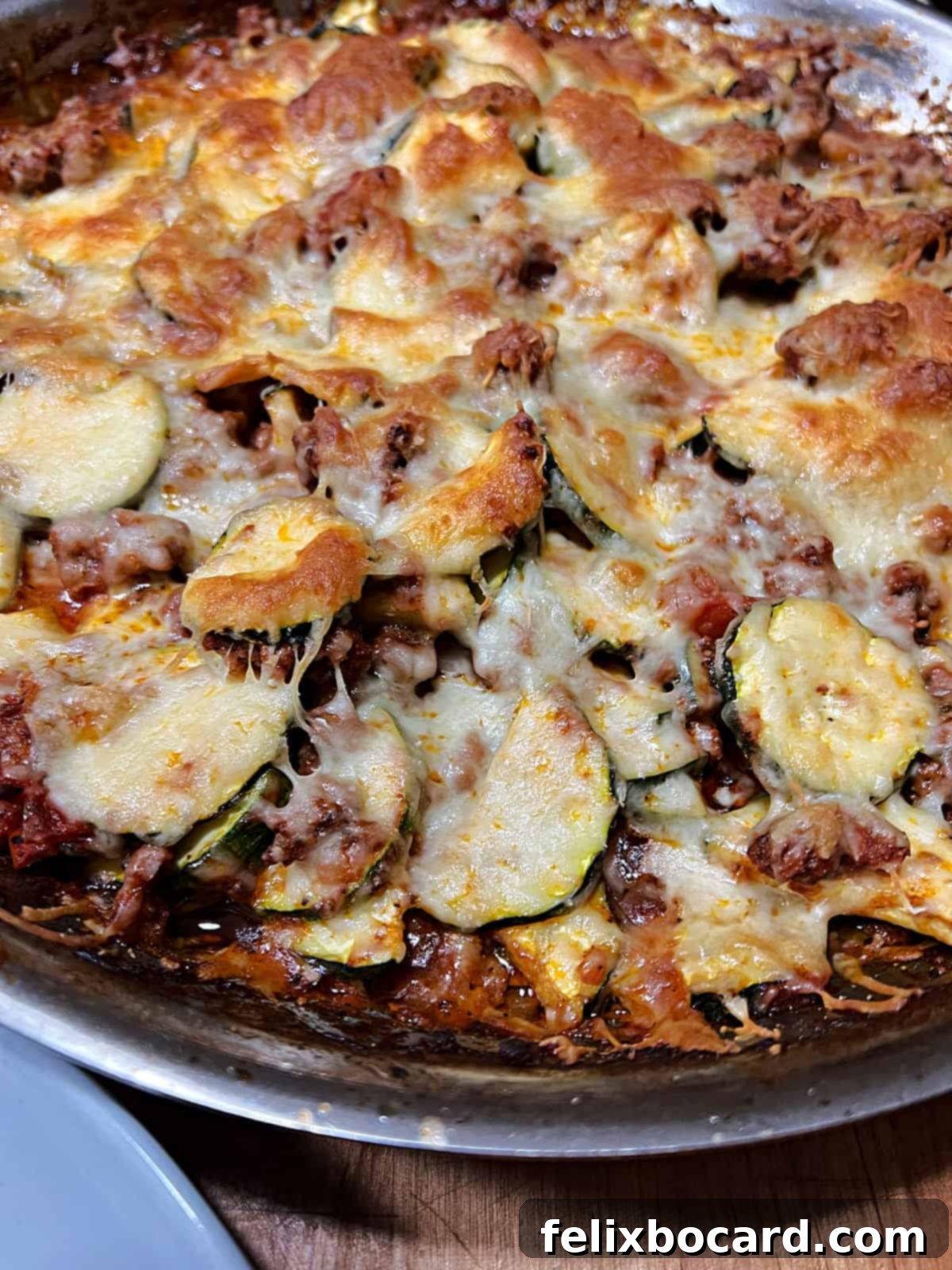 A close-up shot of the perfectly baked zucchini casserole, showing the rich, bubbly cheese and tender ingredients.