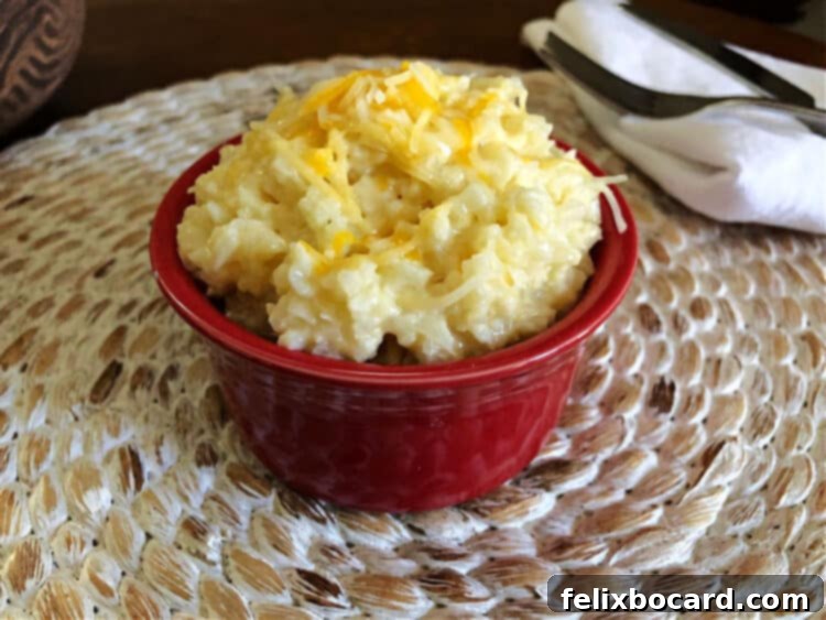 Guilt Free Cheesy Cauliflower Rice 3 A small red bowl filled with steaming cheesy cauliflower rice, ready to be served