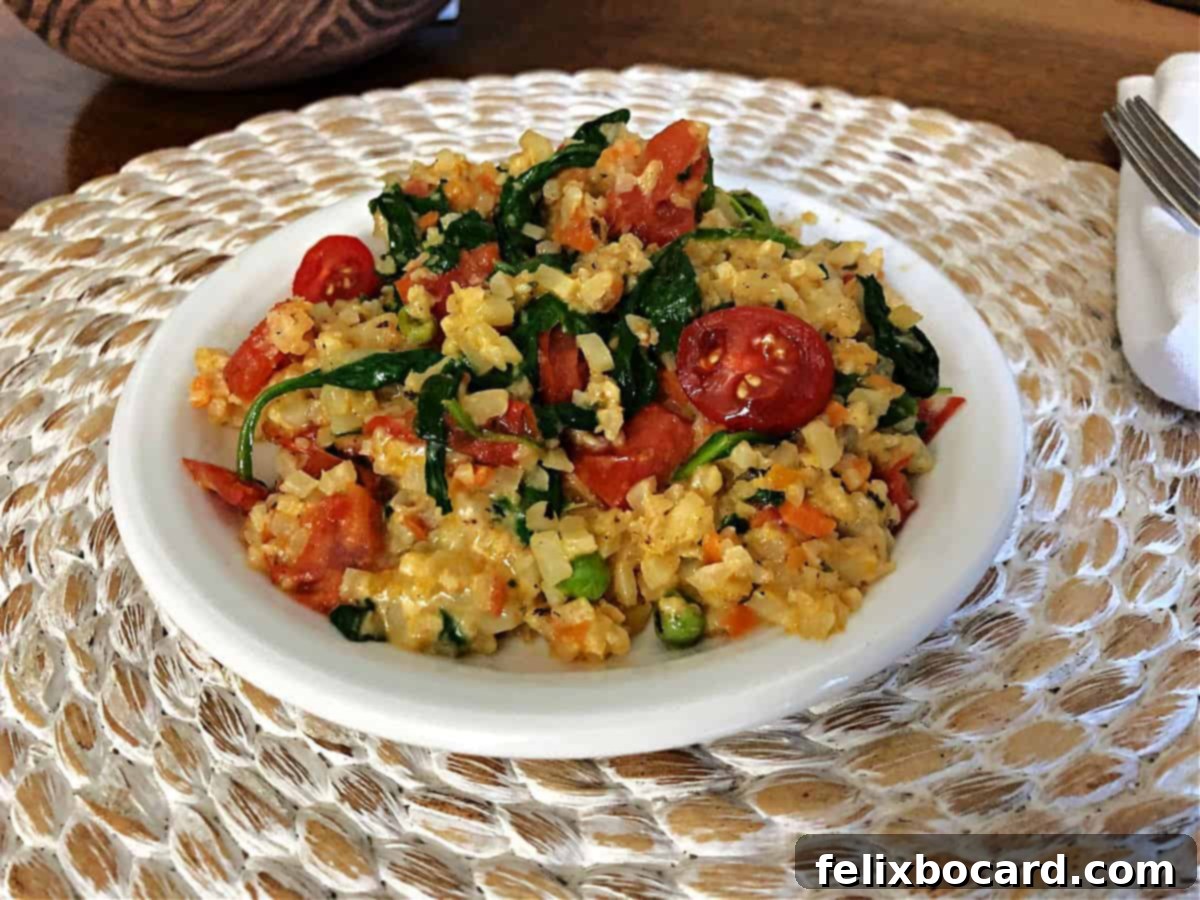 Guilt Free Cheesy Cauliflower Rice 5 Cheesy cauliflower rice with fresh spinach and diced tomatoes, offering a colorful and healthy twist