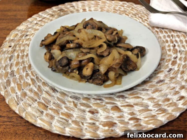 Individual serving of sautéed mushrooms and onions on a small white plate, garnished with fresh herbs, ready to be enjoyed.