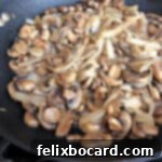 Close-up of sautéed mushrooms and onions in a skillet, showcasing their golden brown perfection.