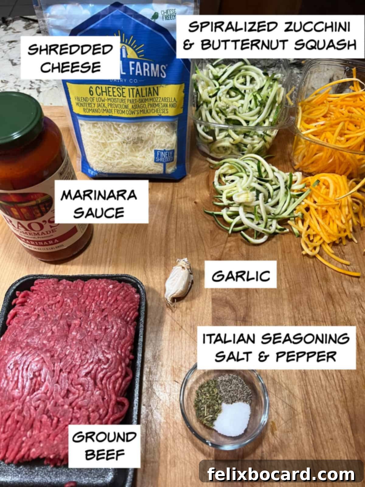 Ingredients laid out: shredded Italian cheese blend, spiralized butternut squash, minced garlic, marinara sauce, raw ground beef, Italian seasoning, and salt and pepper.