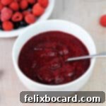 A square image of a bowl of keto sugar-free raspberry sauce, ready to serve.