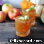 Caramel Apple Vodka Indulgence 5 Two caramel apple cider vodka drinks garnished with apple cubes and cinnamon, whole apples behind.