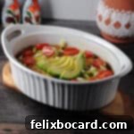 keto taco casserole in an oval dish garnished with green onions, tomatoes and a sliced avocado