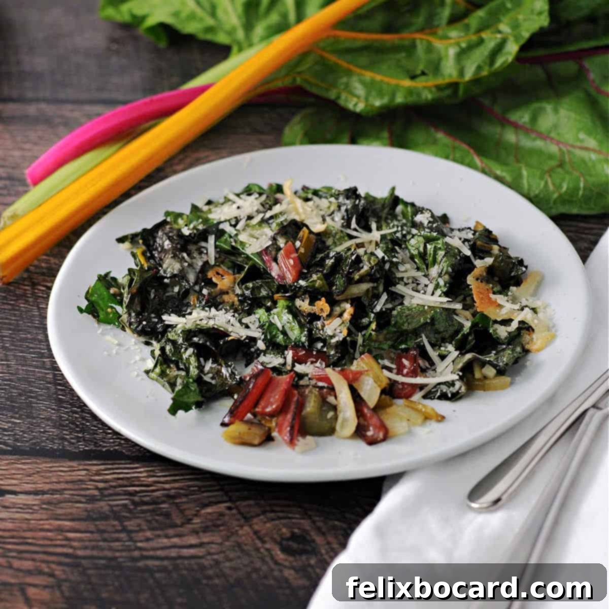 Close-up of freshly roasted Swiss chard with melted Parmesan cheese on a white plate, ready to be served.