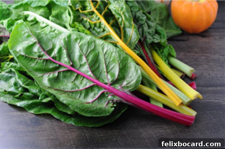 Vibrant raw rainbow Swiss chard showcasing its red, yellow, and white stems against lush green leaves, ready for preparation.
