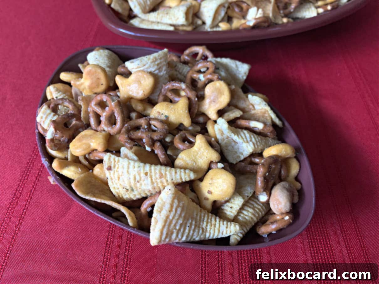 A festive football-shaped bowl filled with vibrant ranch party mix, showcasing a delightful blend of crackers, pretzels, and Bugles.