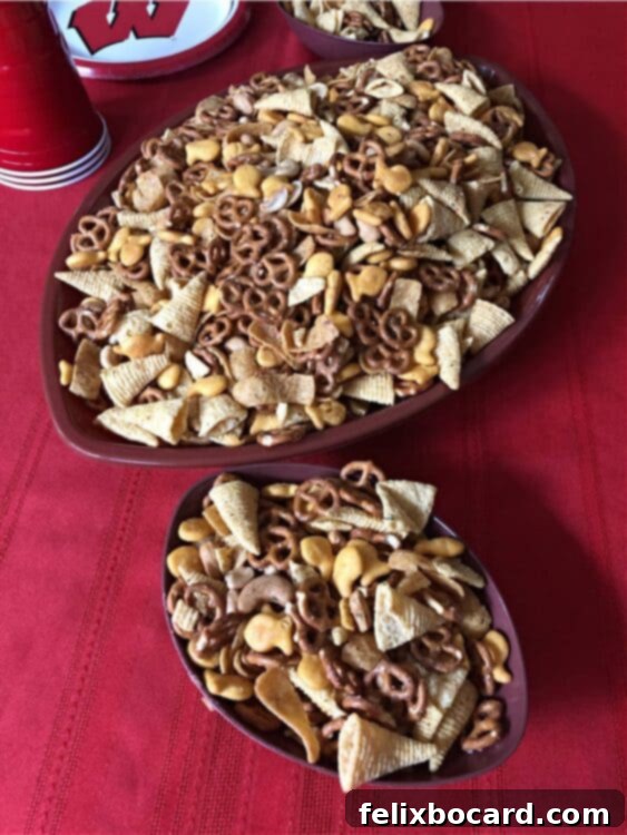 Two football-shaped bowls brimming with ranch party mix, ready for serving at a festive gathering.
