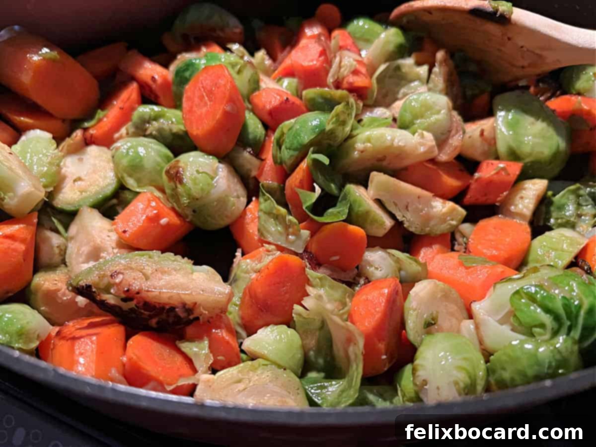 Crispy Brussels and Sweet Carrots 2 Perfectly cooked Brussels sprouts and carrots, lightly browned and glistening, served in a pan on a stove top.