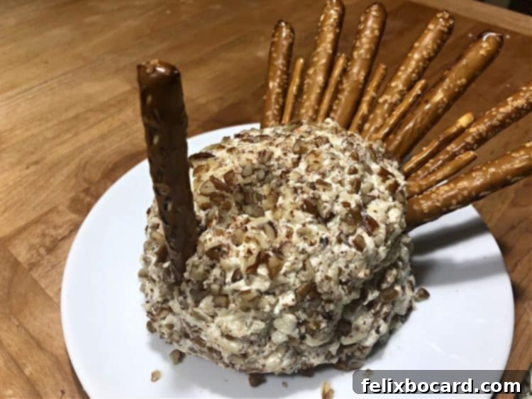 Inserting a pretzel rod to form the turkey's neck for the cheese ball.