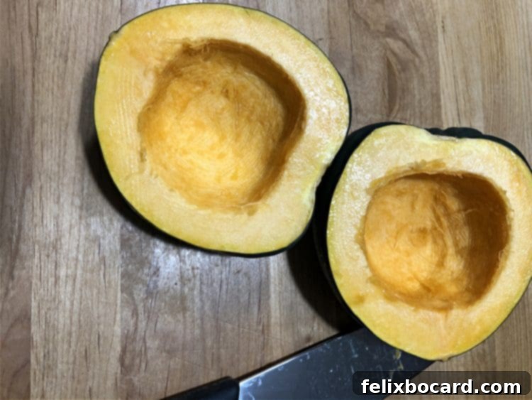 Raw acorn squash cut in half, revealing its seeds and ready for preparation
