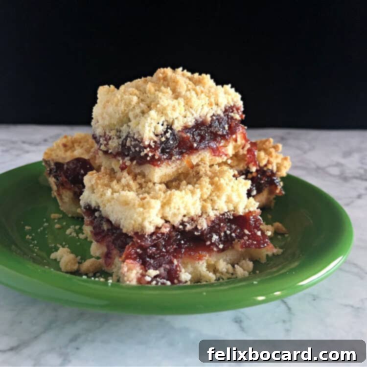 Stack of cranberry sauce bars on a small green plate, garnished with a sprig of fresh cranberries.