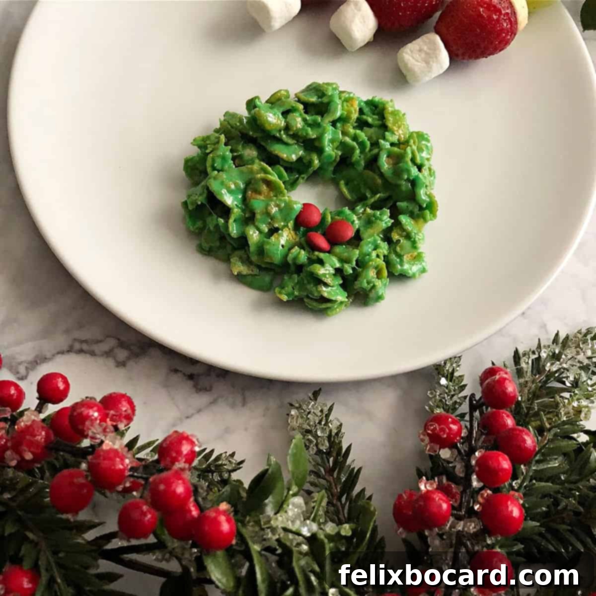 Close-up of a single green cornflake marshmallow cookie wreath, meticulously decorated with small red candies, showcased on a white plate with subtle holiday lighting.