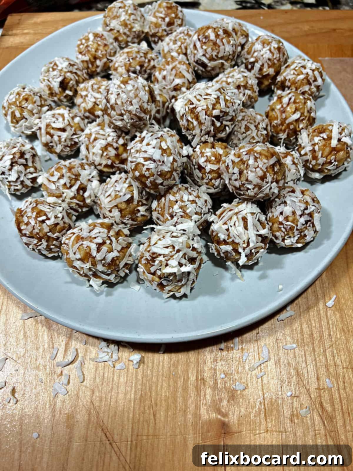 A large plate full of coconut date balls covered in coconut.