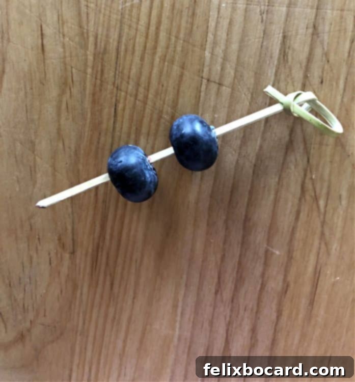2 blueberries speared by a bamboo pick