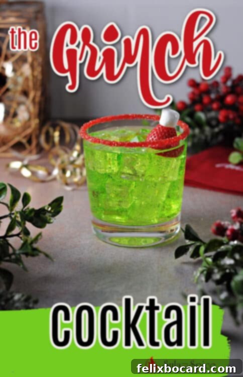 Grinch cocktail with red sugar rim and strawberry garnish on a festive background.