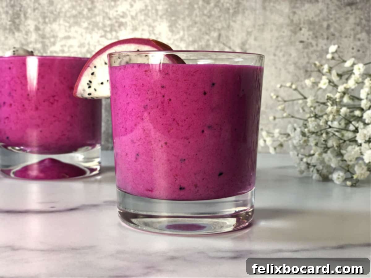 A glass of magenta colored dragon fruit smoothie garnished with chia seeds and coconut, ready for a healthy start to the day.