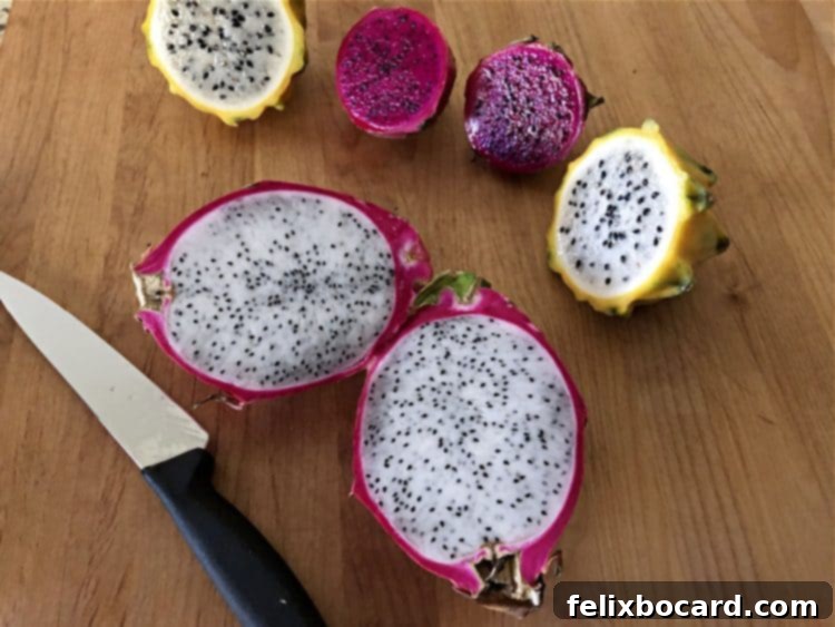 Three varieties of dragon fruit, sliced open to reveal their distinct internal pulps: white pulp with black seeds in one, and vibrant magenta pulp with tiny black seeds in another.