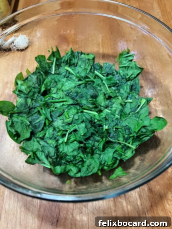 Wilted spinach after a brief microwave heating, showing reduced volume and softened leaves.