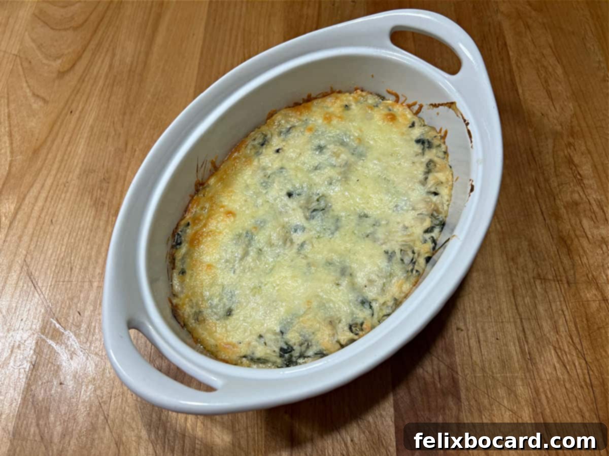Freshly baked keto spinach artichoke dip, hot and bubbly with a golden-brown melted cheese topping, ready to be served.