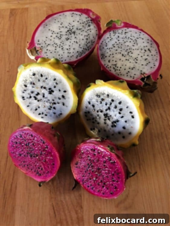 Three different varieties of dragon fruit, cut open, revealing their diverse internal pulp colors and seed patterns.