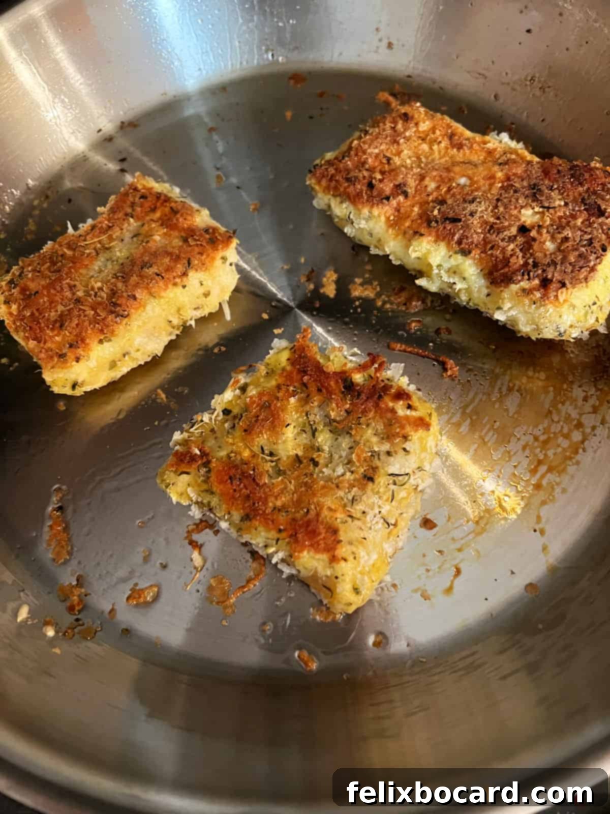 Cod pieces sizzling in a skillet, one side beautifully fried to a golden-brown crust.