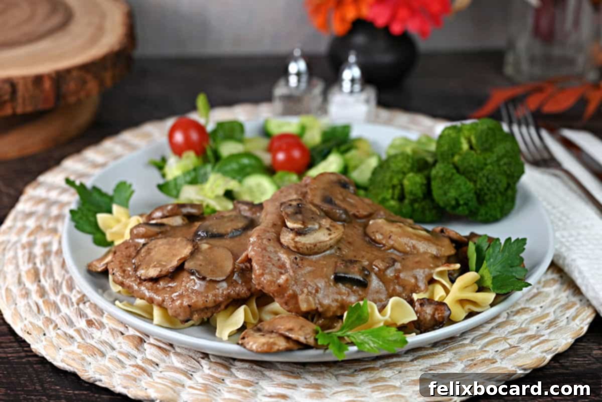 A serving of cube steak made in the Instant pot on a plate with noodles, gravy, salad, and broccoli.