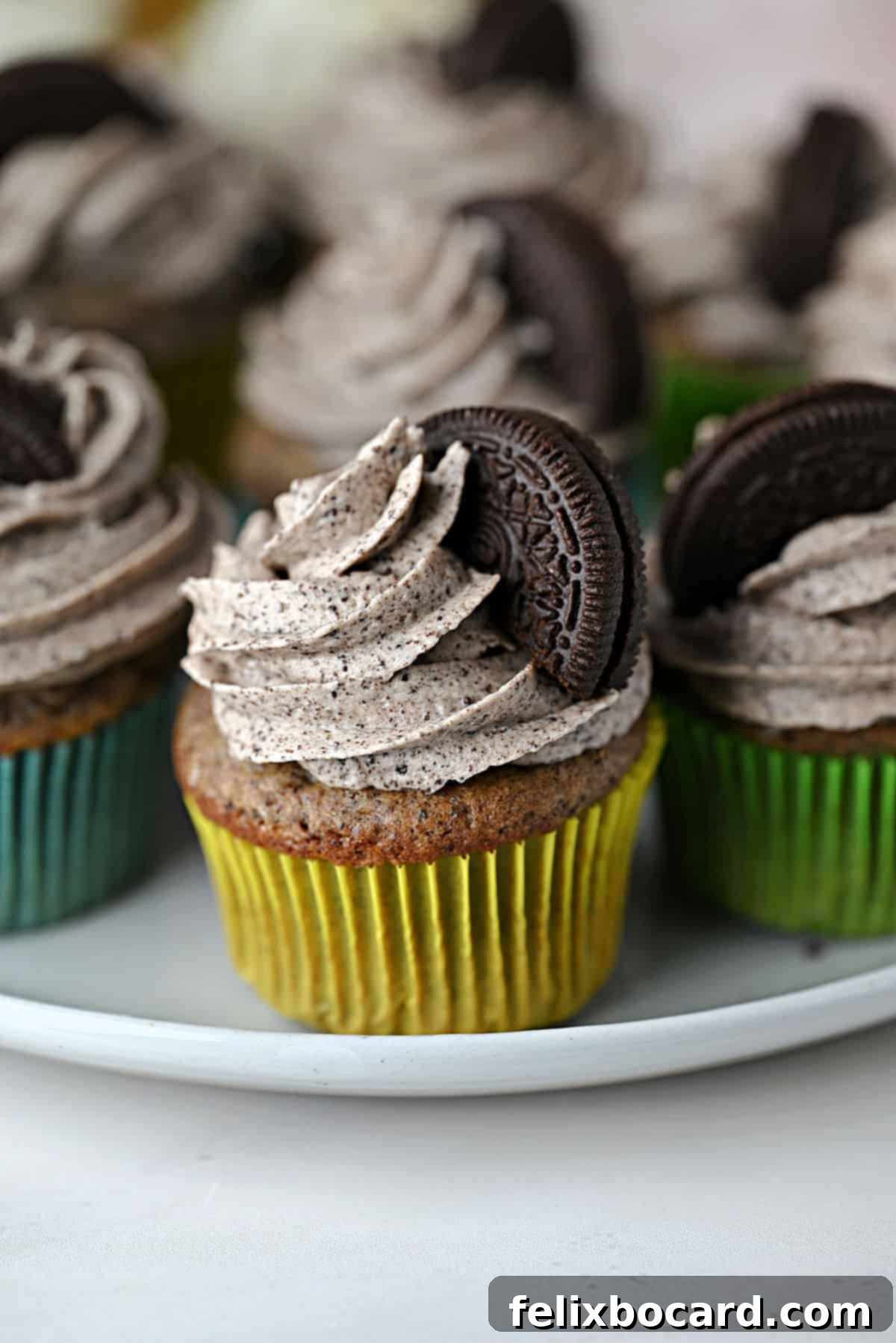 Twelve freshly baked Oreo cupcakes, beautifully frosted and topped with whole Oreo cookies.