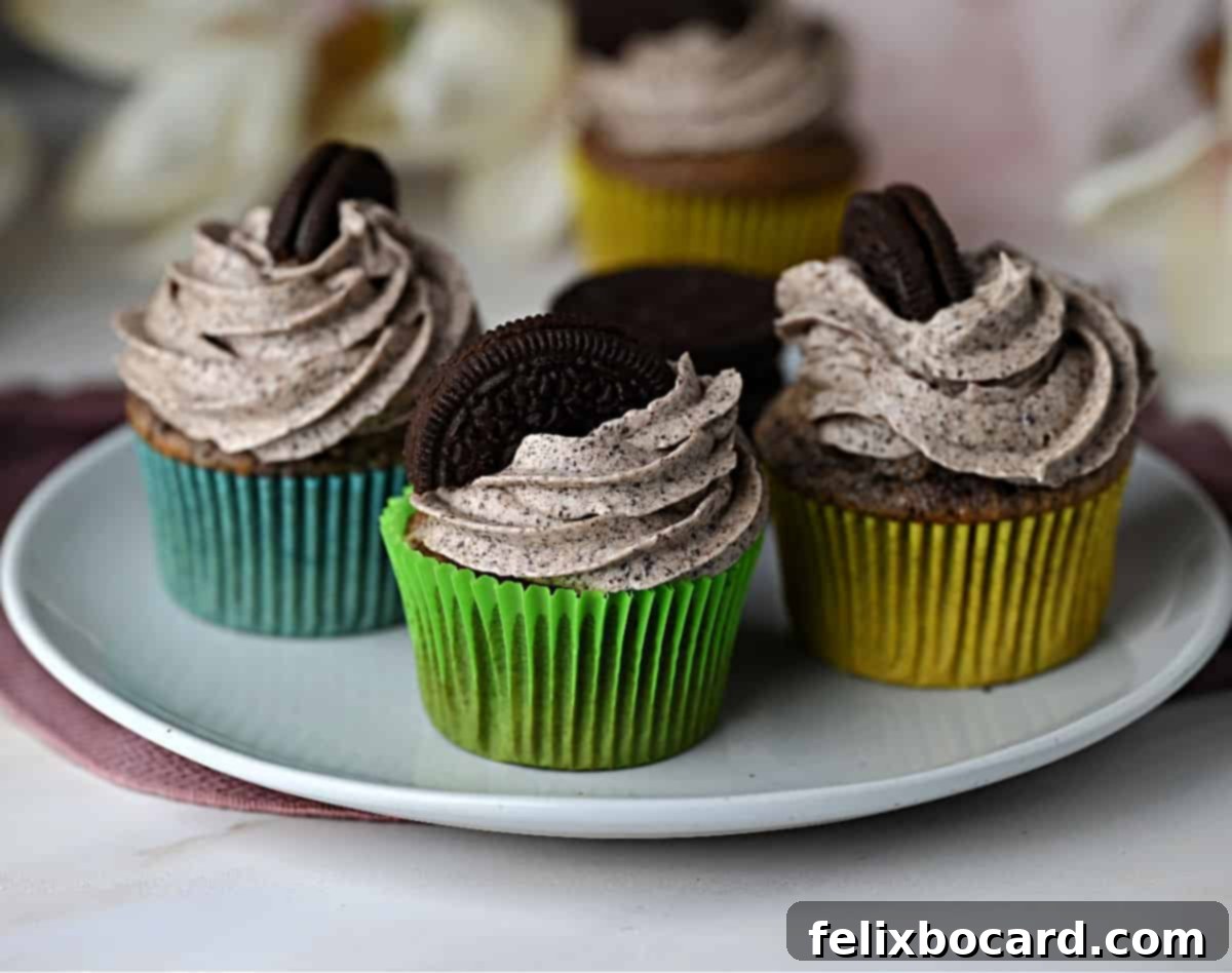Three cupcakes generously frosted with creamy Oreo buttercream frosting and adorned with a whole Oreo cookie on top.
