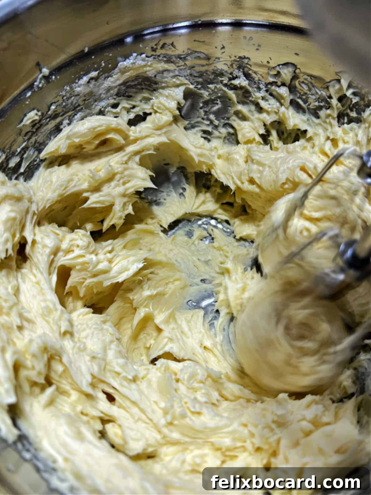 Whipping softened butter until it's light and fluffy in a mixing bowl.