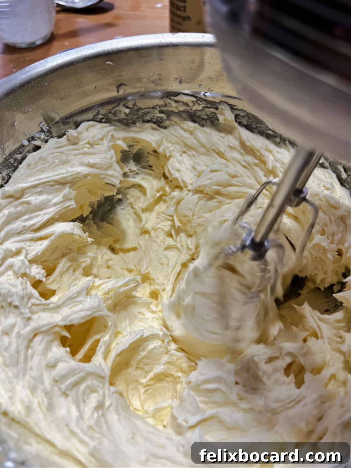 Incorporating powdered sugar into the buttery frosting base.
