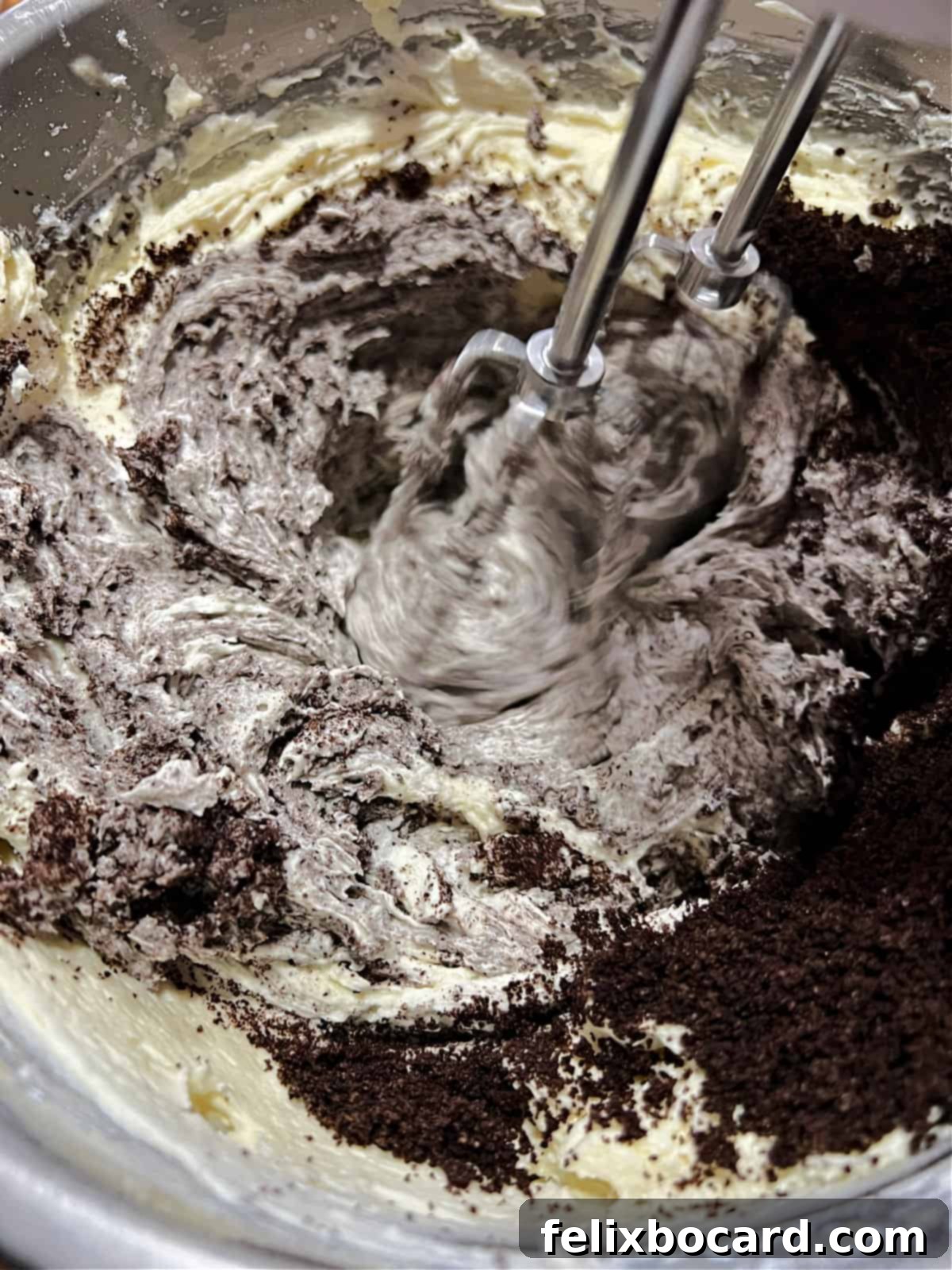 Adding finely crushed Oreo cookies into the rich buttercream frosting.