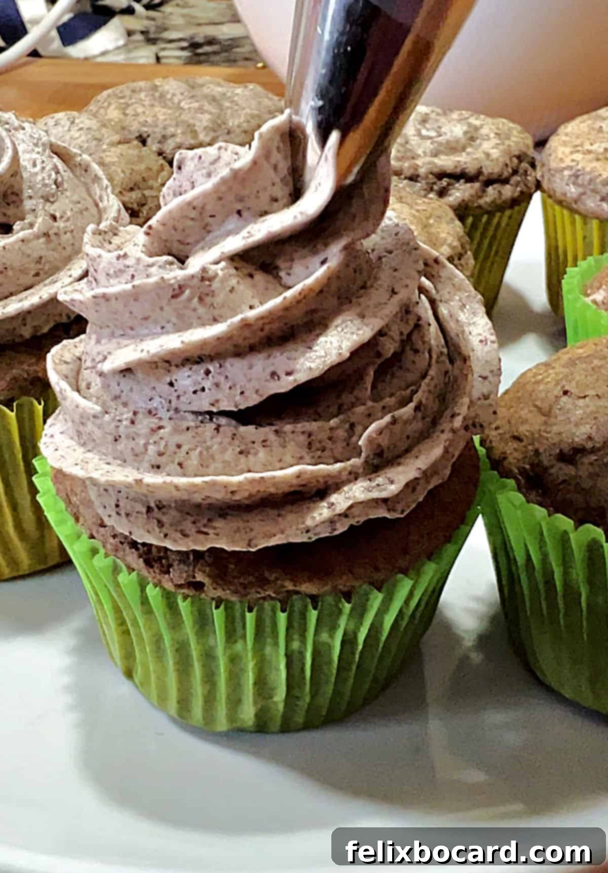 A freshly frosted cupcake with Oreo buttercream being piped onto it.