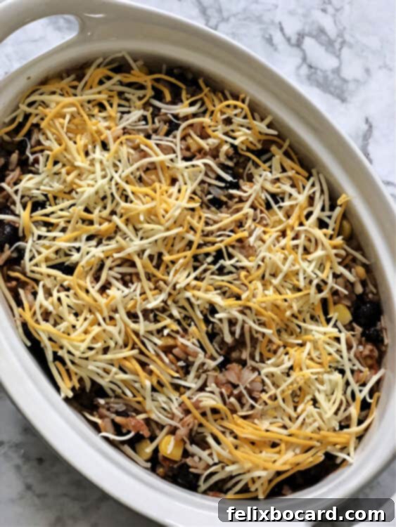 Casserole in an oval dish, ready to bake with cheese on top