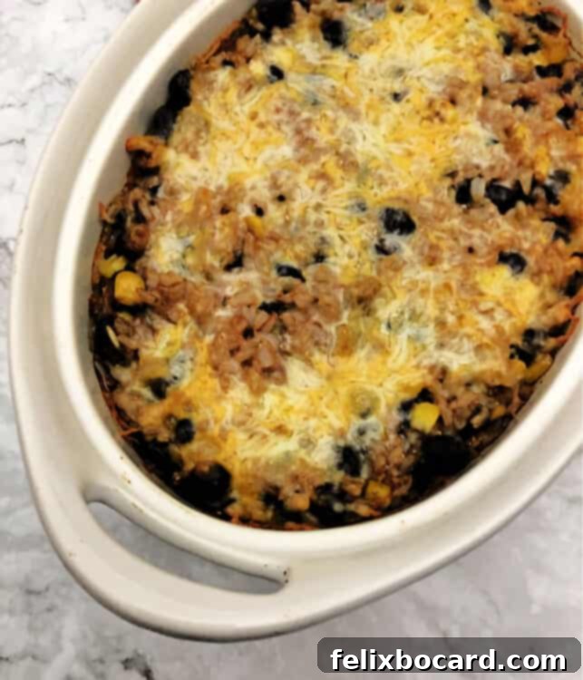 Oval casserole dish with baked black beans and rice inside, bubbly and golden