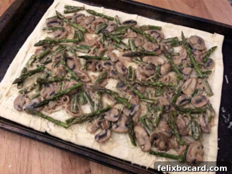 Puff pastry sheet covered evenly with the rich asparagus and mushroom filling