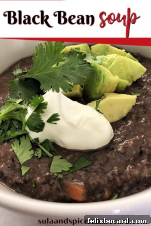 A top-down view of a vibrant bowl of creamy Black Bean Soup, garnished with fresh lime wedges, avocado, sour cream, and cilantro, ready to be enjoyed.