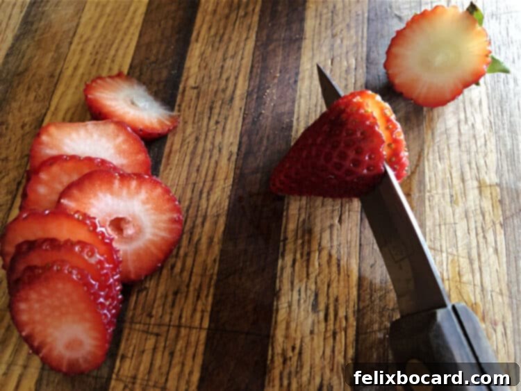 Detailed shot of a knife carefully slicing a fresh strawberry at a slight angle to create an oval shape, perfect for bunny butt pancake footpads.