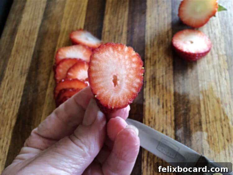 The face of a perfectly cut strawberry slice, demonstrating its desirable oval shape, ready to be placed as a footpad on a bunny butt pancake.