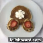 A close-up shot of a delightful bunny butt pancake, showcasing its round pancake body, oval feet, strawberry footpads, and a generous whipped cream tail. This image captures the essence of a fun and festive breakfast.