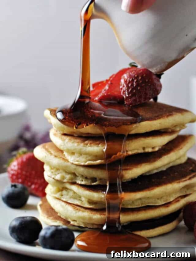 A close-up view of a perfectly cooked stack of golden-brown almond milk pancakes, showcasing their light and fluffy texture, ready to be topped.