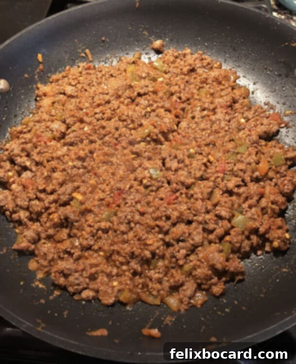 Skillet full of savory taco meat simmering in its delicious sauce.