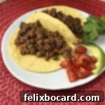 Taco meat in small corn tortillas on a small plate