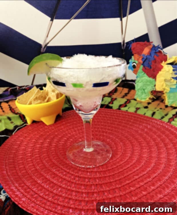 a margarita glass full of the icy slush, surrounded by bright colors and some chips