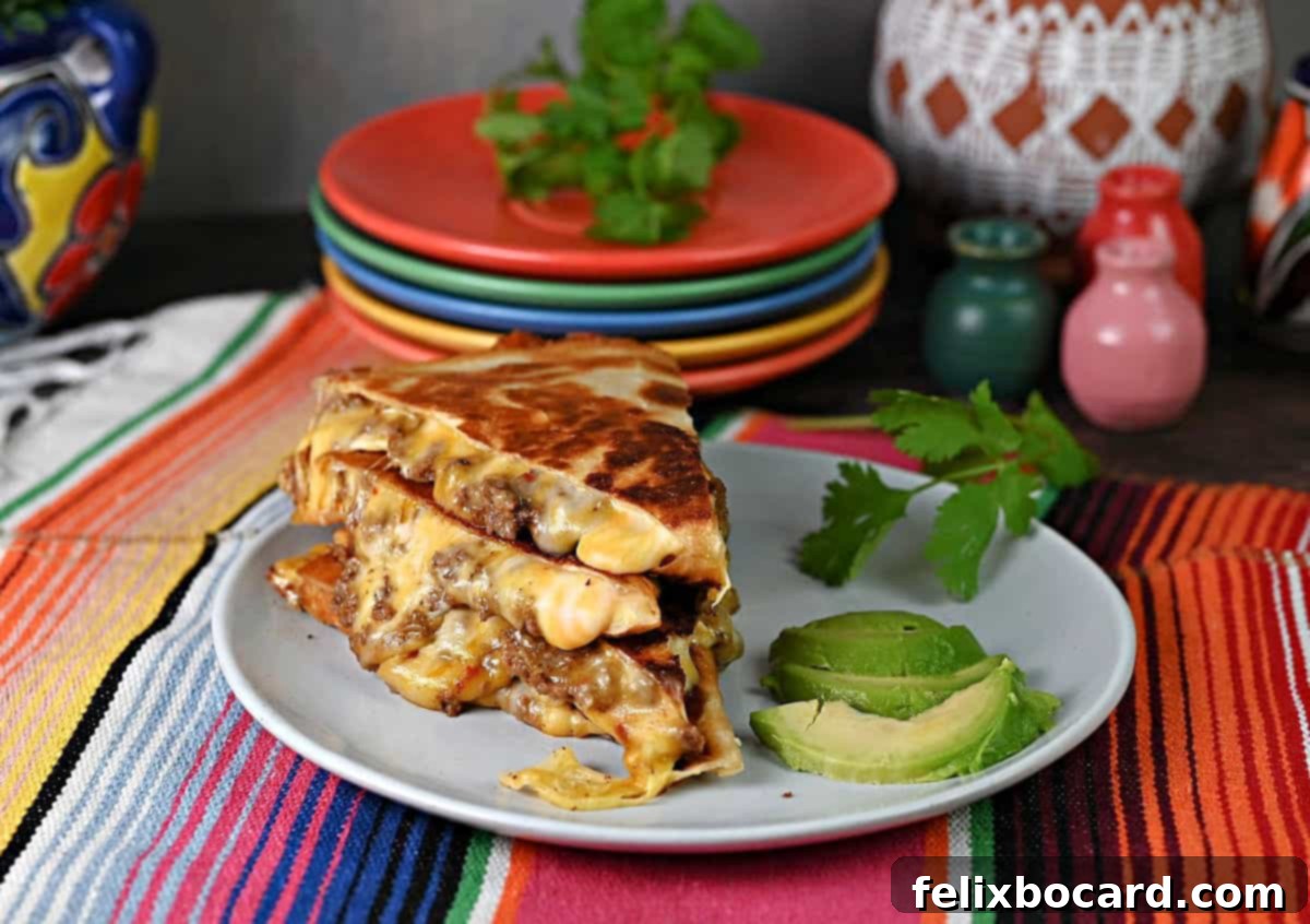 Stack of ground beef quesadilla slices on a plate with avocado and cilantro.