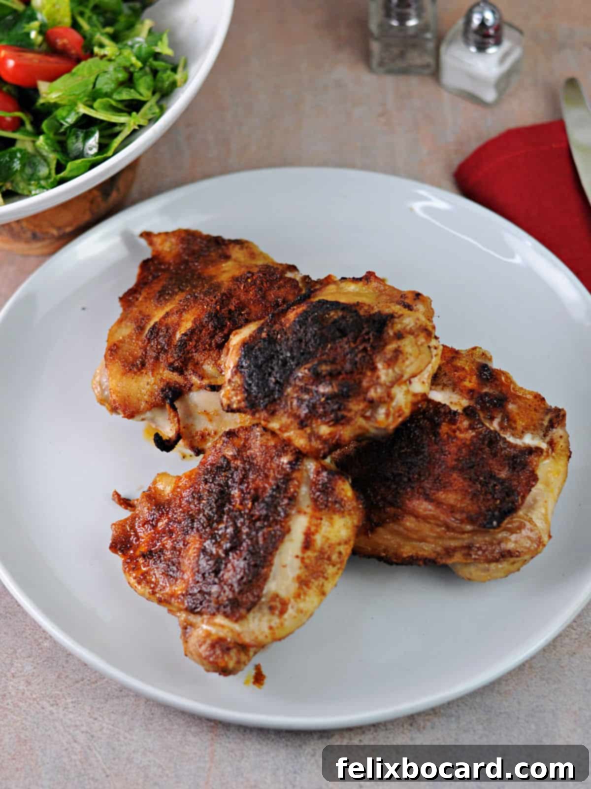 Plate of four golden-brown air fryer cooked chicken thighs, ready to be served.