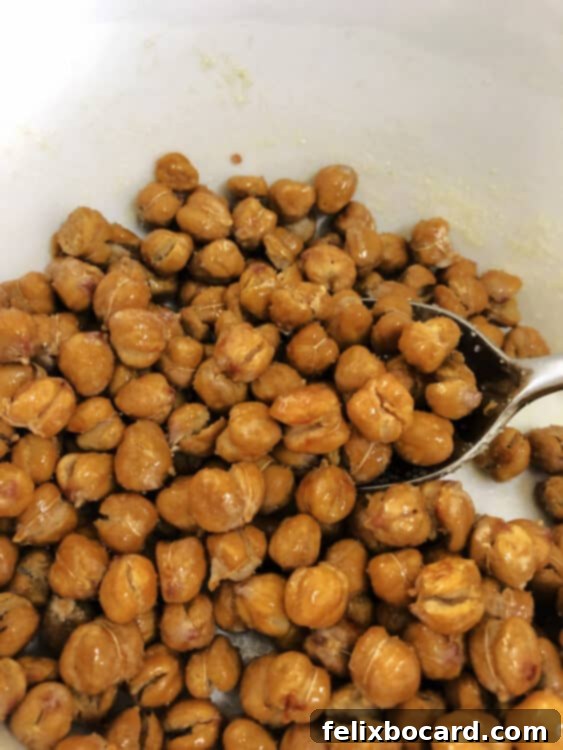 dry roasted chickpeas in a bowl stirring with oil and salt